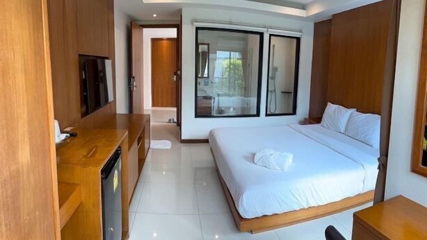 A modern hotel room with a large bed, a wooden desk, a flat-screen TV, and a sliding glass door to the balcony. - The D257 Hotel (Phetchabun)