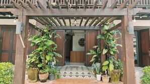A wooden pergola entrance with potted plants, a patterned tiled floor, and a wooden bench inside. - Happy Hour Boutique​ Hotel (Luang Prabang)