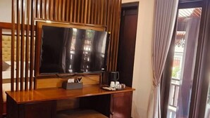 A room with a wooden desk, a television, and a window with curtains. - Happy Hour Boutique​ Hotel (Luang Prabang)