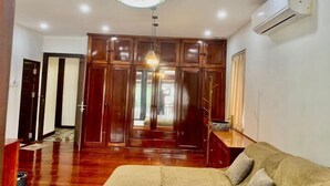 A room with a wooden wardrobe, a sofa, a ceiling light, and an air conditioning unit. - Happy Hour Boutique​ Hotel (Luang Prabang)