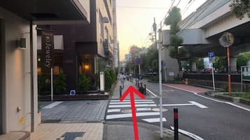 A street view with a pedestrian crossing, a building with a sign, and a blue parking sign.