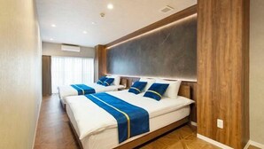Une chambre d’hôtel avec deux lits, un plancher en bois, un grand téléviseur fixé au mur et une fenêtre avec des rideaux.