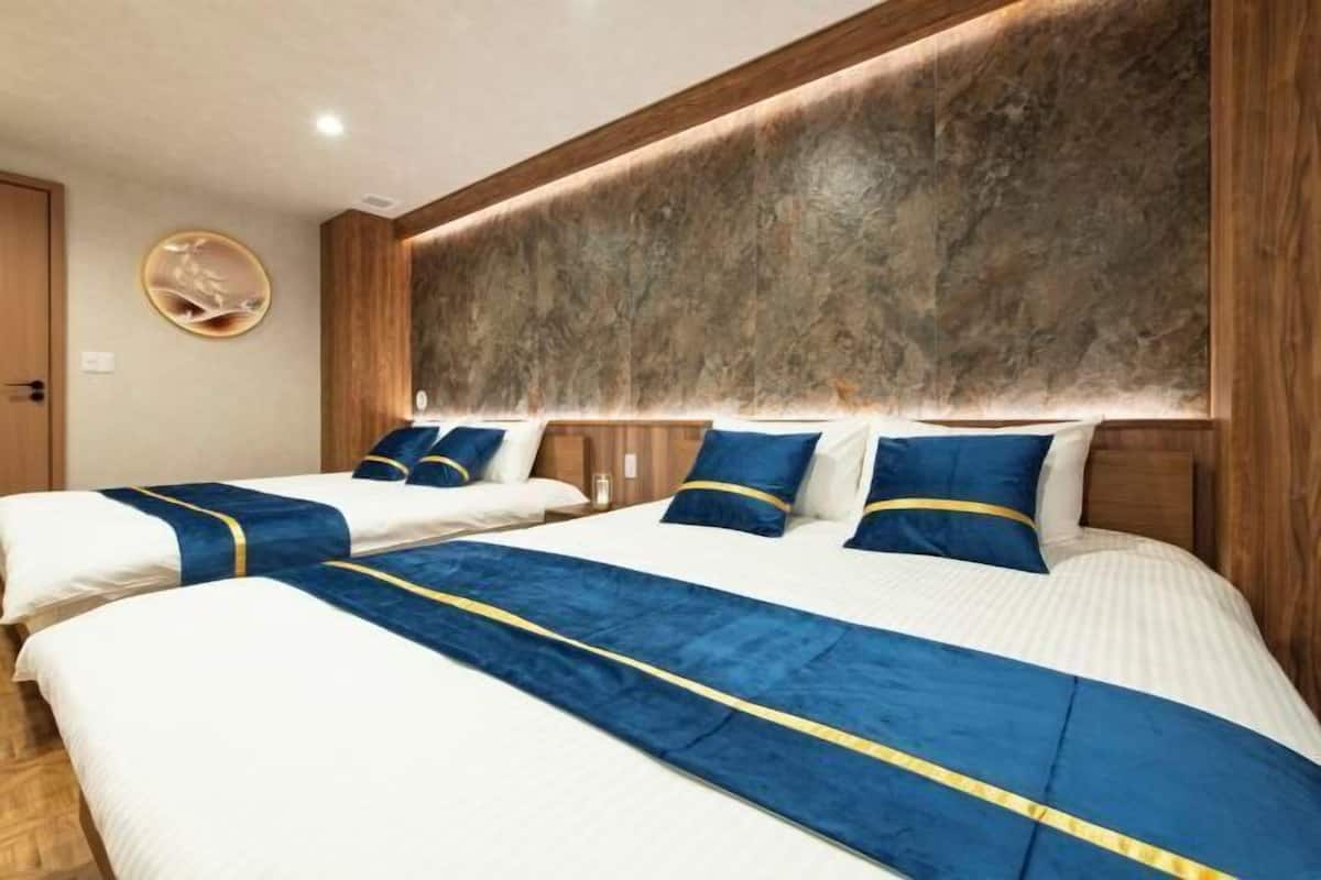 Hotellihuone, jossa on kaksi sänkyä, puinen pääty ja pyöreä seinäkoriste.