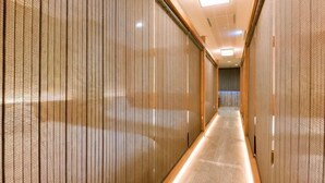 Un couloir avec des stores verticaux, un sol carrelé et un luminaire au plafond.