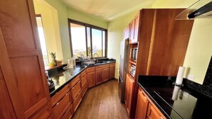 Une cuisine avec des meubles en bois, un plan de travail noir et un réfrigérateur en acier inoxydable.