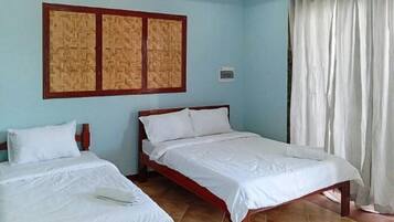 A room with two beds, a woven headboard, a curtain, and a tiled floor.