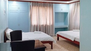 A hotel room with two beds, a desk, and a chair. - McKinley Grand Marina Hotel and Resort (Guihulngan)