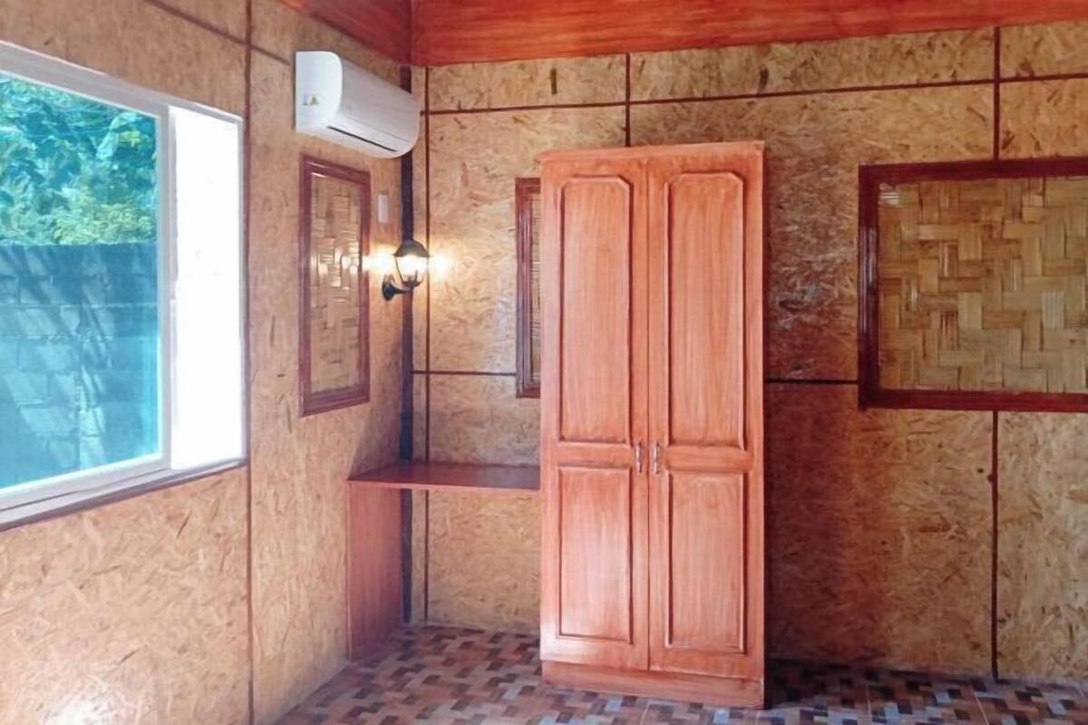 A room with wooden walls, a built-in wardrobe, a bench, and a wall-mounted light fixture.
