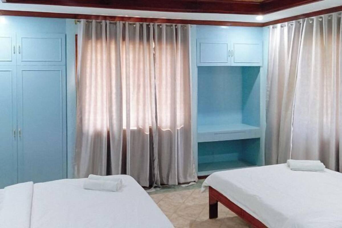 A room with two beds, a built-in bench, and a wardrobe.