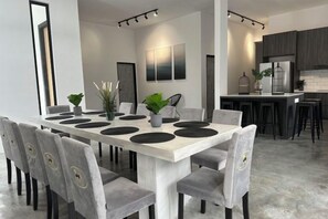A modern dining area with a long table, grey upholstered chairs, and a minimalist decor.