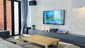 Een moderne woonkamer met een flatscreen televisie aan de muur, een houten salontafel en een bank.