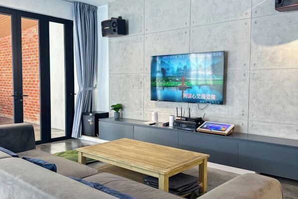 A modern living room with a flat-screen TV mounted on the wall, a wooden coffee table, and a sofa.