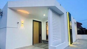 Een modern gebouw met een witte gevel, een houten deur en een klein entreegebied met treden.