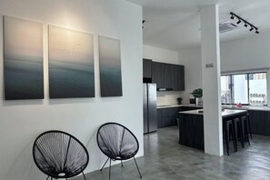 Eine moderne Küche mit Edelstahlgeräten, einer Bar mit Hockern und einem großen Fenster, das für natürliches Licht sorgt.
