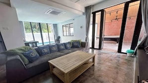 Een moderne woonkamer met een hoekbank, een houten salontafel en grote schuifdeuren die uitkomen op een terras.