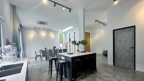 Une cuisine moderne dotée d’un îlot central, de tabourets de bar et d’un coin repas avec des chaises et des tables.