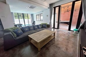A modern living room with a sectional sofa, a wooden coffee table, and large windows. - The Luxurious 27, Johor Bahru (Johor Bahru)
