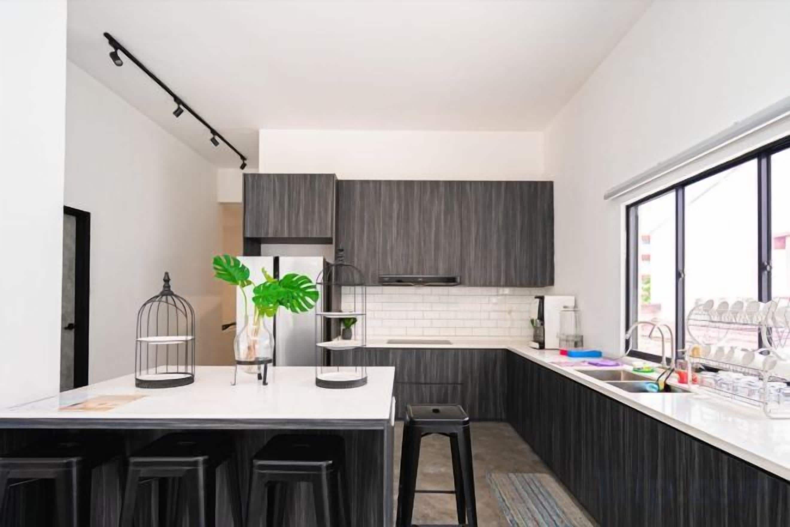Una cocina moderna con armarios oscuros, una encimera blanca y un taburete de bar.