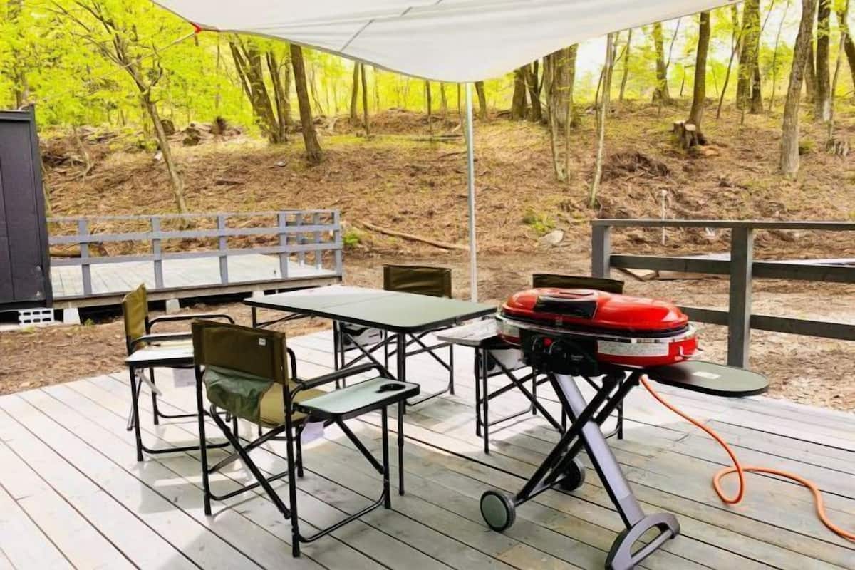 A deck with outdoor furniture, a grill, and a tent.