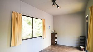 A room with a large window, a wooden floor, a ceiling light, and a small shelf with items. - Bulls Camp -Guesthouse with pets at the foot of World Heritage Mt.Fuji- (Narusawa)
