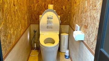 Une petite salle de bain compacte, équipée de toilettes, d’un bidet et d’un sèche-mains.