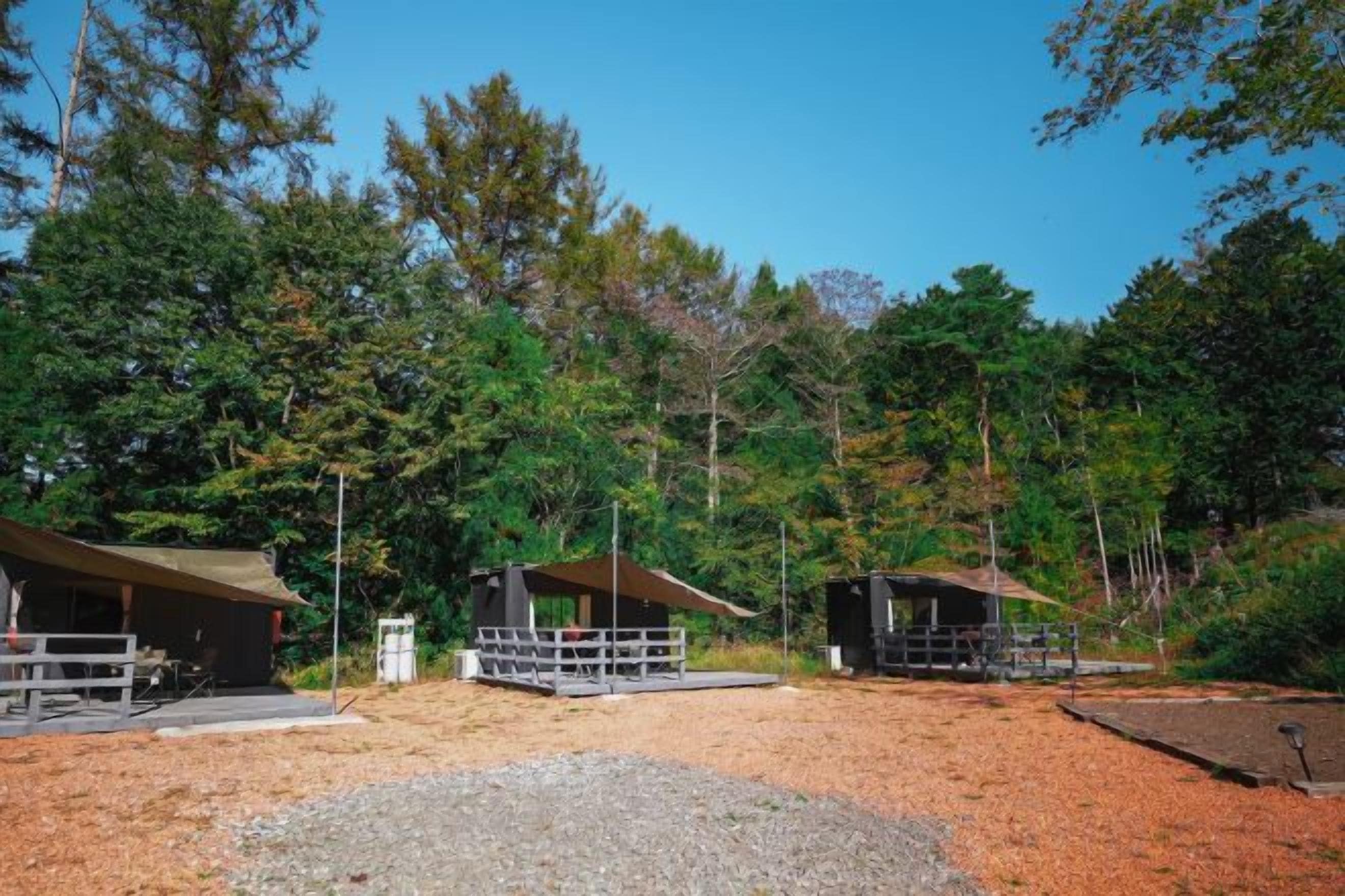 Um parque de campismo com duas cabanas, cada uma com um espaço exterior murado e uma área de estar coberta.