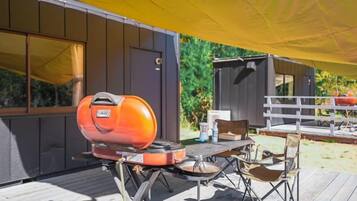 Une terrasse extérieure équipée d’un barbecue, d’une table et de chaises.