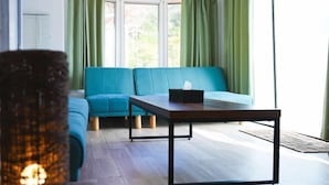 A modern living room with a teal sofa, a wooden coffee table, and green curtains. - Bulls Camp -Guesthouse with pets at the foot of World Heritage Mt.Fuji- (Narusawa)