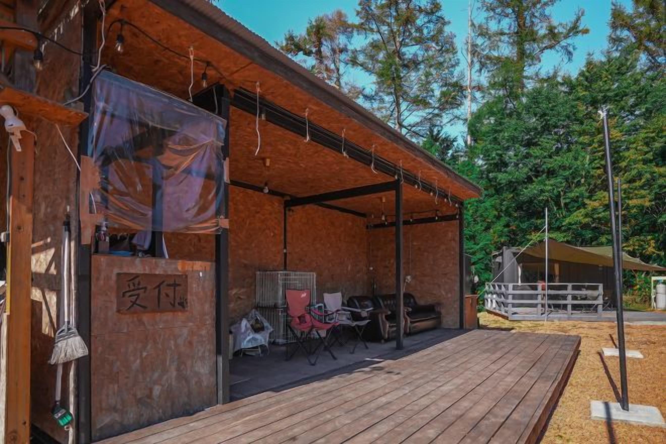 A wooden building with a covered outdoor area, a sign with Chinese characters, and a fenced area with a horse.
