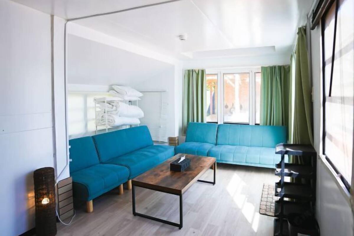 A modern living room with a blue sofa, a wooden coffee table, and a window with curtains.