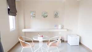A small room with a round table, two chairs, a white cabinet, and three wall-mounted pictures. - Shi-ro-i Poshtel (Hat Yai)