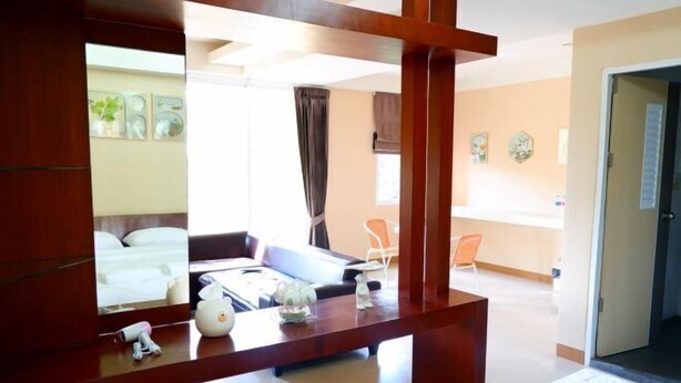A hotel room with a wooden desk, a mirror, a bed, a sofa, and a small stool. - Shi-ro-i Poshtel (Hat Yai)