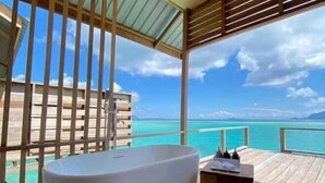A bathroom with a freestanding bathtub, wooden deck, and a view of the ocean. - Sisipan Island Water Resort (Semporna)