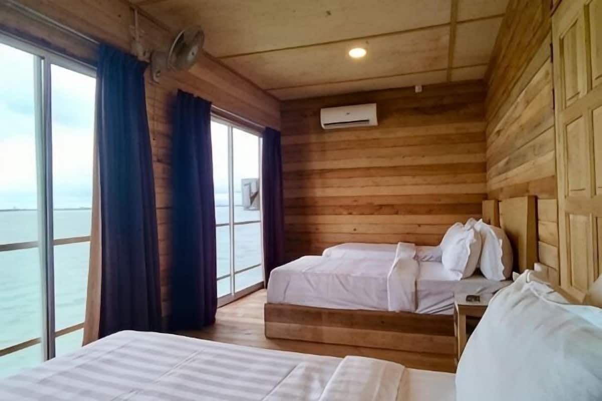 Een blokhut met twee bedden, een raam met gordijnen en een airconditioning.