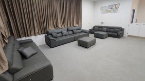 A modern living room with a sectional sofa, ottoman, and a large curtain wall. - Seawind Garden (Semporna)