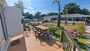 A balcony with a table and chairs, surrounded by a metal railing and potted plants. - Seawind Garden (Semporna)