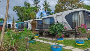 A row of modern RVs with a grassy area and potted plants in front. - Seawind Garden (Semporna)