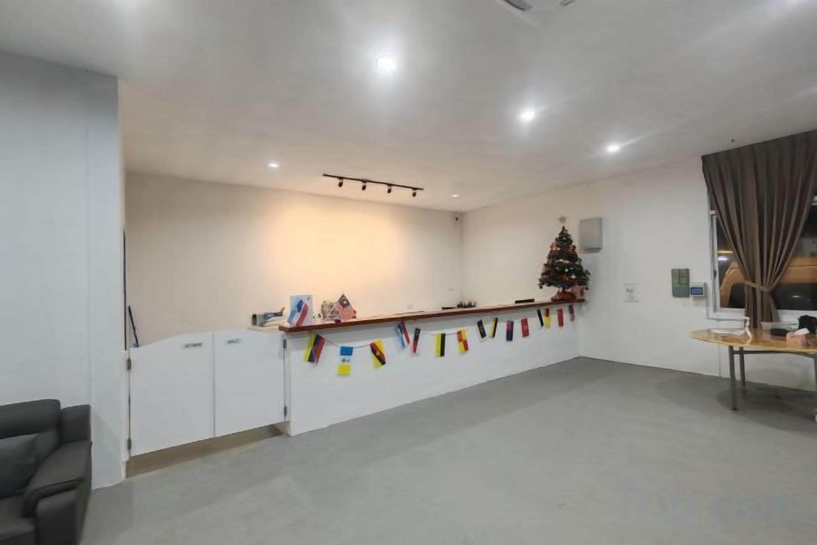 Un'area reception di un hotel con un lungo banco, un albero di Natale e una finestra con tende.