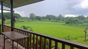 A wooden deck with a railing overlooking a green field.