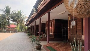 A building with a covered porch, wooden columns, and a tiled entrance.