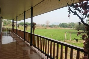 Un espacio al aire libre cubierto con piso de madera y baranda, con vista a un campo verde.