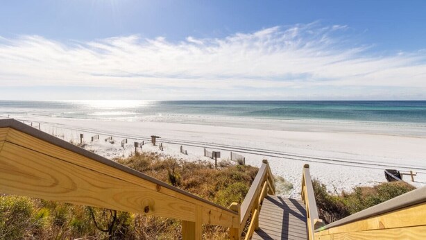Eine Holztreppe führt zu einem Strand mit freiem Blick auf den Ozean.