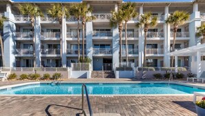 Ein Hotel mit Swimmingpool, mehreren Balkonen und Palmen.