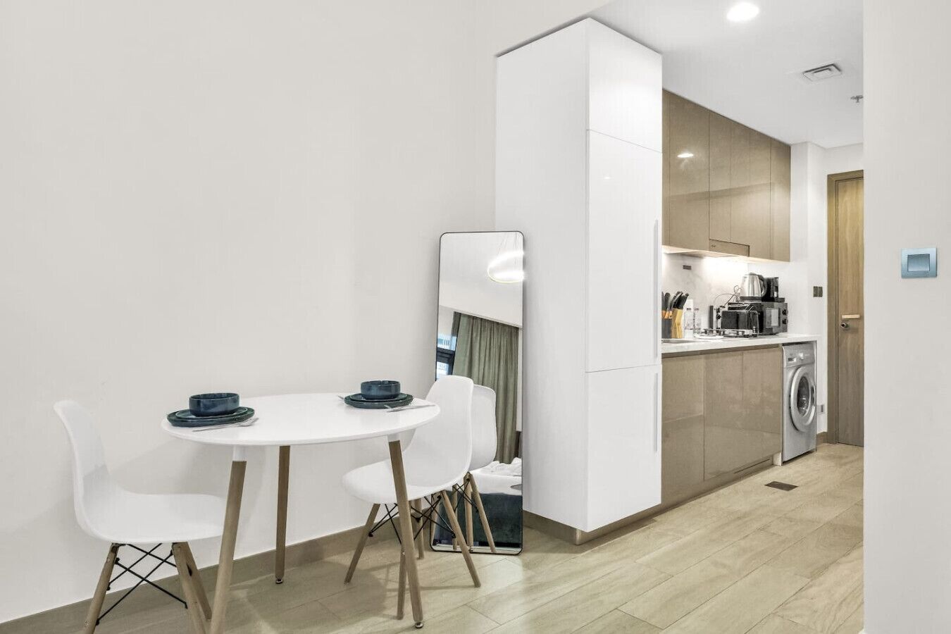 Een functionele ruimte met een eethoek, een kitchenette en een wasmachine.