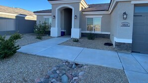 A residential building with a garage, a driveway, and a small garden area with rocks and plants.