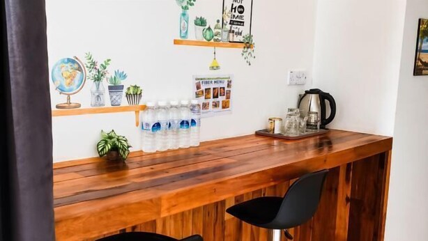 Un coin bar en bois avec deux chaises noires, un globe terrestre, des plantes en pot et une affiche du menu imprimée sur du papier.
