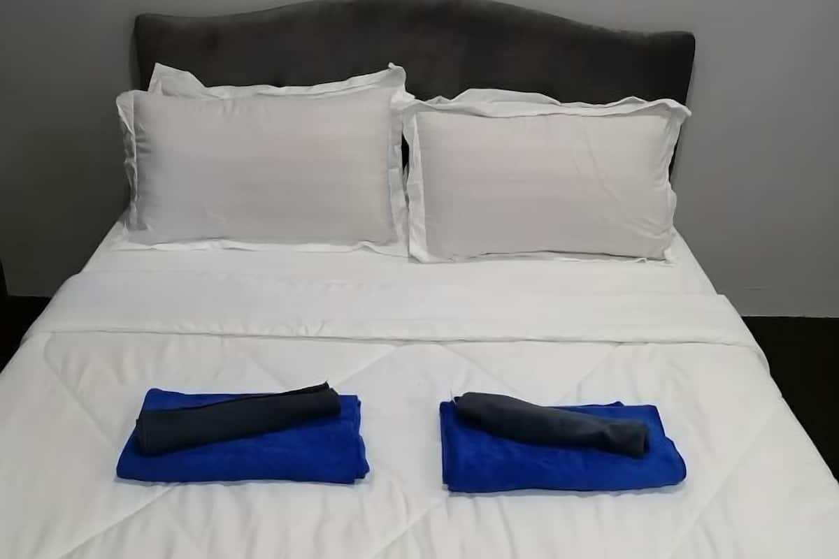 A bed with white bedding, two pillows, and two folded blue blankets.