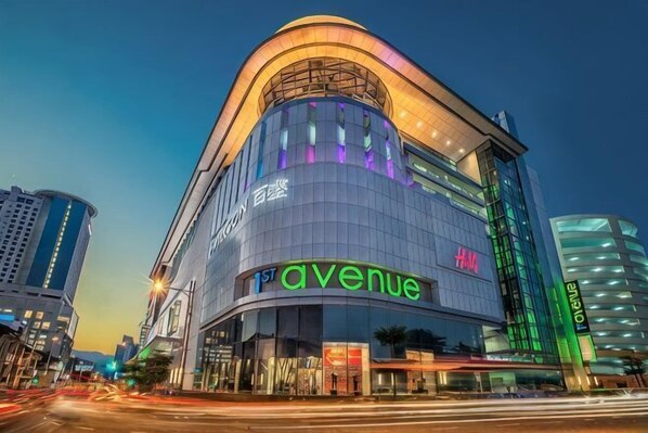 A modern building with a curved facade, the word 'avenue' prominently displayed, and a large H&M store on the ground floor. - sungai ujong homestay (George Town)