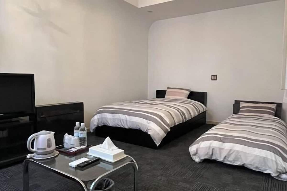 A hotel room with two beds, a TV, a coffee maker, and a small table with toiletries.