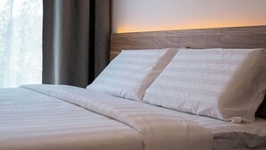 A neatly made bed with white linens and a wooden headboard. - Semporna Seaview Hotel (Semporna)